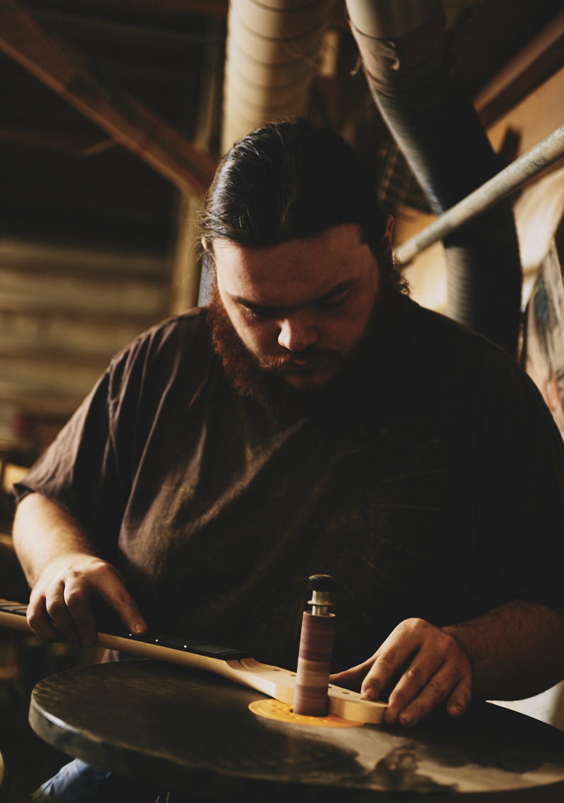 Craftsman puts finishing details on guitar for a brand library photoshoot