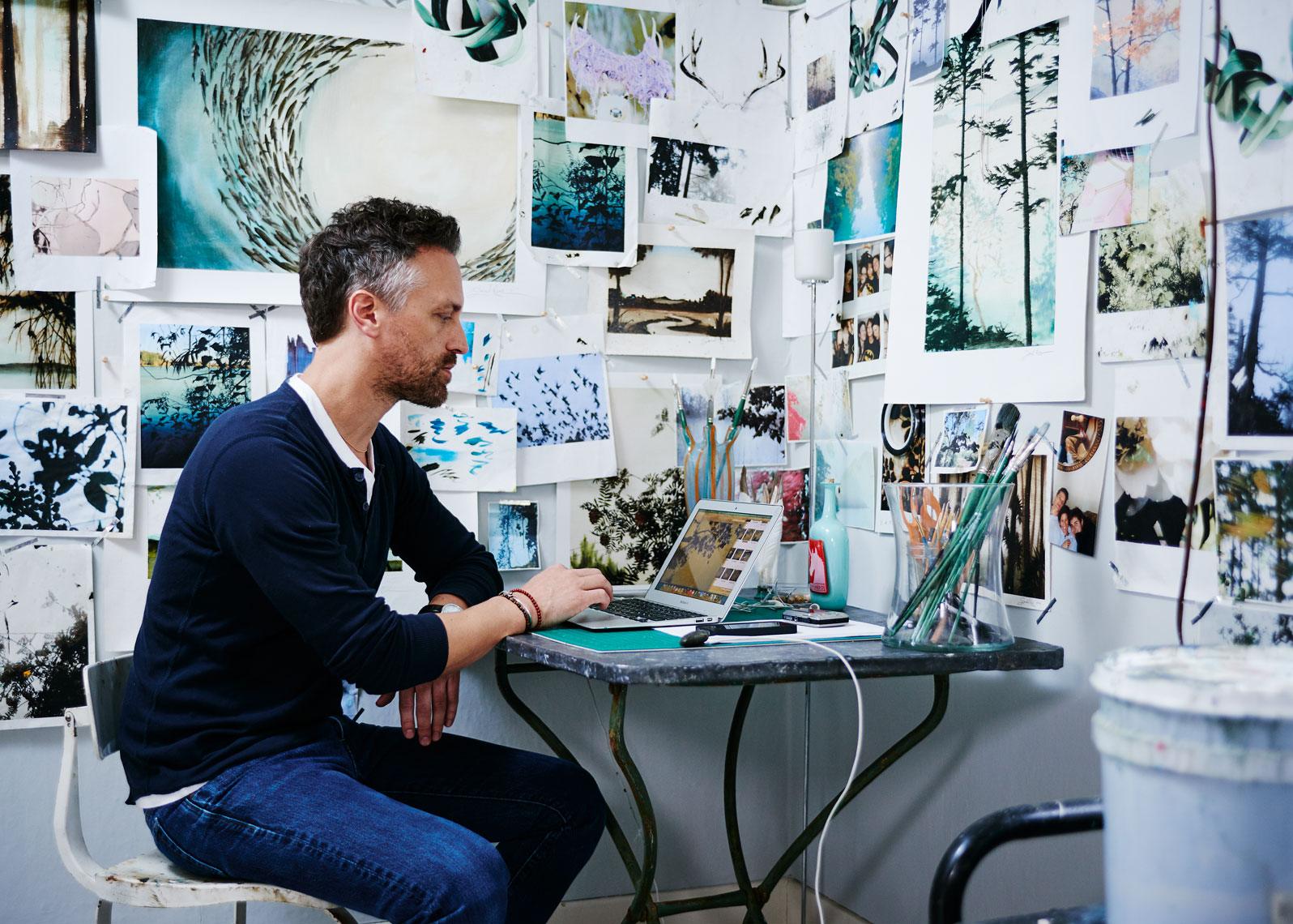 Artist Jared Rue sits at his desk 